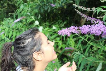 smiling-young-woman-standing-by-flowering-plant